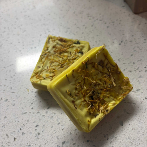 Calendula Soapbar solid yellow-green bars with translucent surfaces and visible dried flower petals throughout