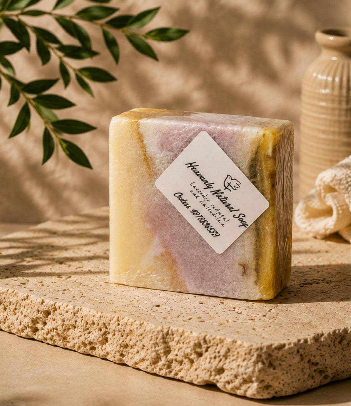 Soap bar in marbled cream, lavender, and golden hues, with a handcrafted appearance and a paper label; Lavender Oatmeal and Calendula