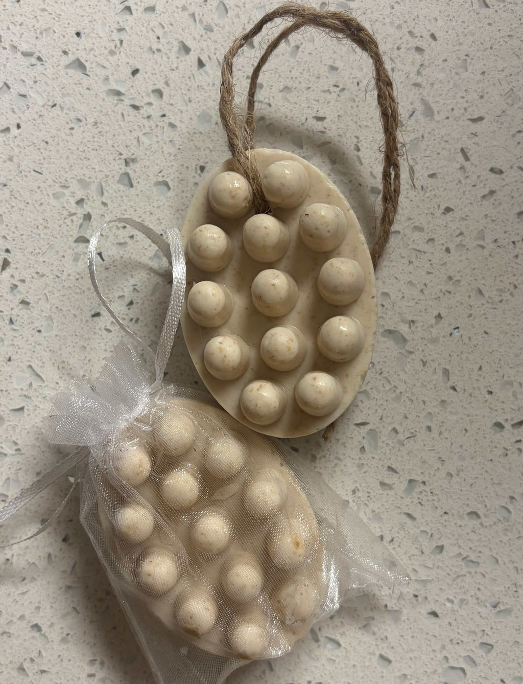 Oatmeal Scrub Soapbar in a cream oval shape with raised round bumps, tied with a natural brown cord.